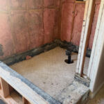 The old tile has been removed in the shower area.